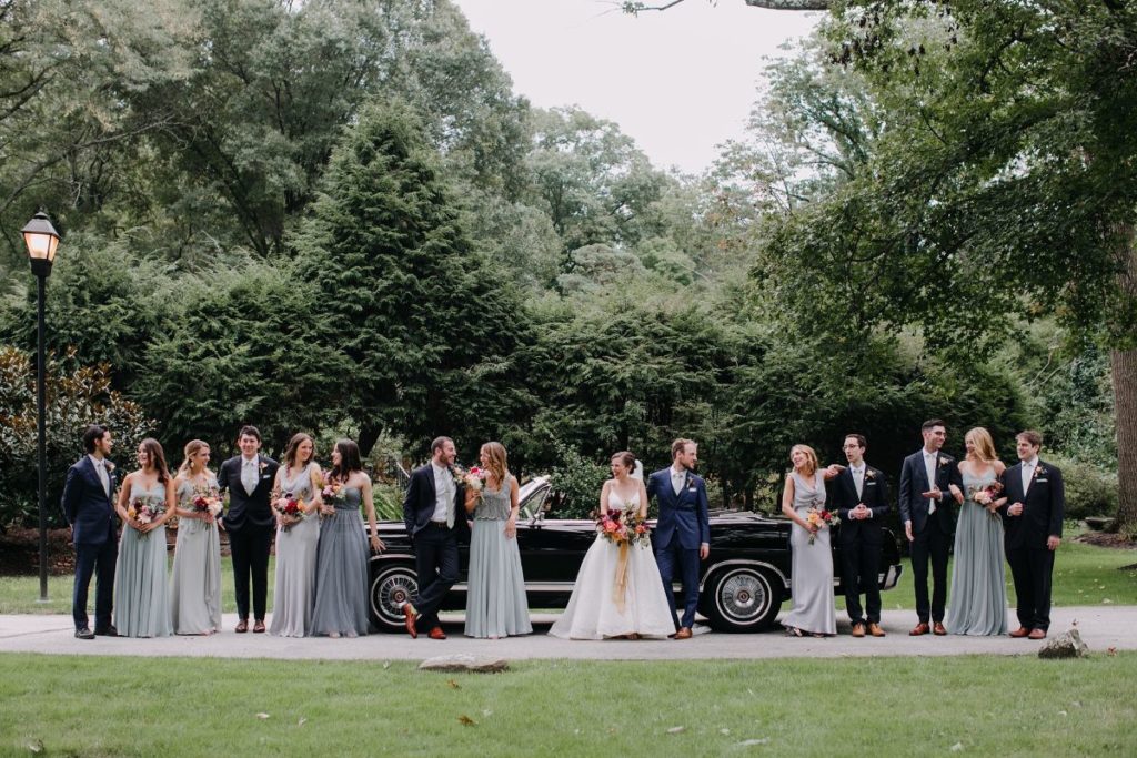 bridal party in front of a luxury convertible