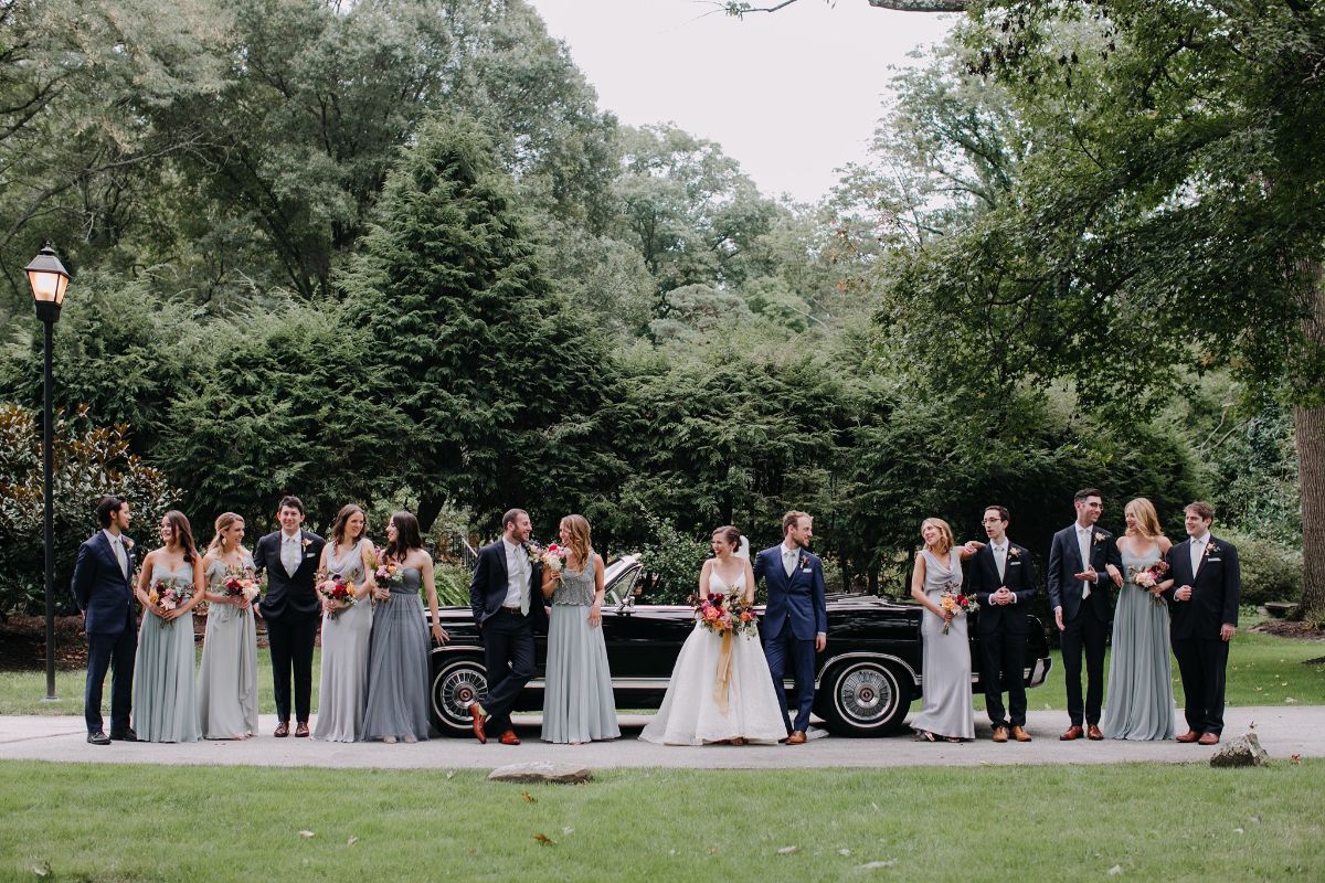 bridal party in front of a luxury convertible